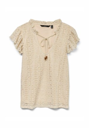 Blouse en dentelle beige avec un col en V, des manches courtes volantées et un détail à cordon rehaussé de perles en bois.