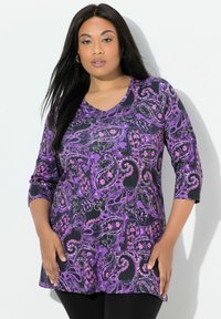 Lila Tunika mit Paisley-Muster, V-Ausschnitt und ¾-Ärmeln, aus leichtem Stoff gefertigt, mit kontrastierenden schwarzen Akzenten.