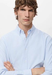 Lichtblauw-wit gestreept overhemd met knopen en een kraag, voorzien van lange mouwen en een zachte katoenen textuur.