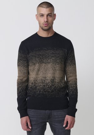 Suéter con degradado negro y marrón, con un cuello y puños acanalados. La textura parece suave con un diseño moteado. Se lleva con jeans grises.