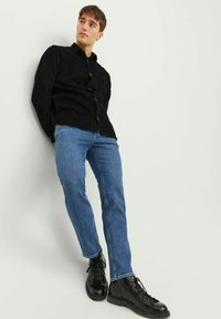 Must mustree kootüüpne särk, sinised denim püksid ja mustad nööbitavad saapad. Särgil on peen tekstuur ning püksid on sirged.