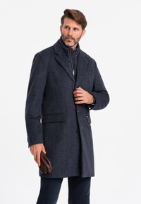 Merijalkaväen kuviollinen takki, jossa on terävät kaulukset, kaksi etutaskua ja napit. Alla on kerroksittain lämmin, korkeakauluksinen vuorattu takki. Pitelee ruskeita käsineitä.