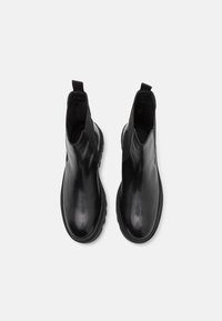 Bottines en cuir noir avec une finition lisse, bout rond, panneaux latéraux élastiques et languettes pour un enfilage facile. Semelle en caoutchouc pour une meilleure adhérence.