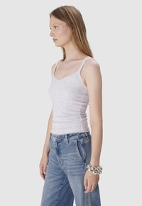 Jasnoszara prążkowana bluzka na ramiączkach z cienkimi paskami, dopasowany krój i dekolt w serek, zestawiona z granatowymi dżinsami z wysokim stanem.