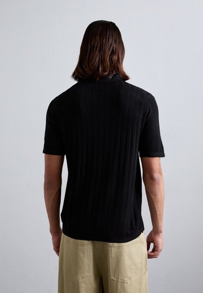 Polo din tricot negru, cu mânecă scurtă, cu textură ribbed și tiv drept, având guler clasic și detalii la spate.