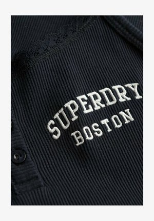Black ribbed fabric with black buttons, lace trim, and white embroidered text reading "SUPERDRY BOSTON."