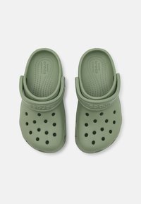 Zelené dreváky s textúrovaným povrchom, s ventilačnými otvormi, zadným popruhom a logom "CROCS" po boku. Vyrobené z ľahkého materiálu.