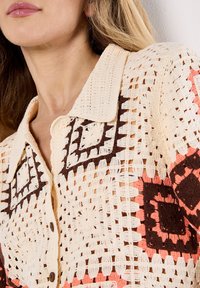 Camicia in pizzo con bottoni, caratterizzata da un motivo a quadrati in beige, marrone e corallo. Design con colletto e texture a trama aperta.