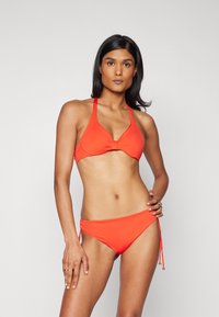 Rød bikini-sett med en halterneck topp som har en knute-detalj og justerbare sideknuter. Glatt, elastisk materiale.
