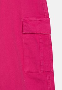 Pantaloni cargo rosa acceso con tasca laterale con pattina, realizzati in tessuto resistente. Superficie testurizzata con dettagli di cucitura visibili.