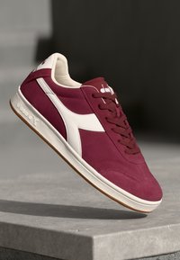 Adidași retro burgundy cu accente albe, design cu șireturi, material din suede, talpă din cauciuc texturat și logo-ul prominent al mărcii pe limbă.