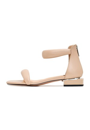 Sandale din piele bej cu toc mic, având un brâu pentru degetul mare și un brâu pentru gleznă. Textură netedă cu un design minimalist.