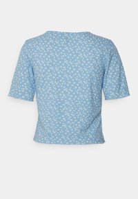 Jasnoniebieska bluzka z krótkim rękawem w kwiatowy wzór. Teksturowany materiał, okrągły dekolt i luźny krój.