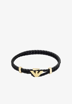 Sort flettet læderarmbånd med en guldfarvet metalklips med et emblem. Glat tekstur og elegant design med karakteristiske detaljer.