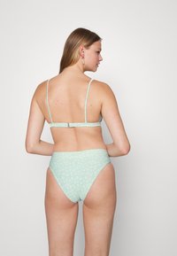 Conjunto de bikini verde-menta com um top texturizado de alças finas e parte de baixo de cintura alta adornada com um subtil padrão floral.