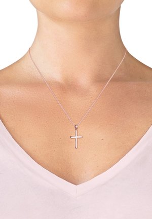 Sølvbelagt halskæde med et lille kors vedhæng, der har et slankt, minimalistisk design og en fin kæde, hvilede på en lys V-hals top.