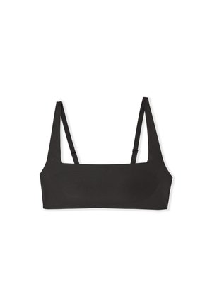 Bralette negro minimalista con tirantes delgados ajustables y escote recto, colocado sobre una superficie blanca.