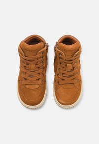 Baskets montantes en daim brun avec un design à lacets, fermeture éclair sur le côté, col rembourré et semelle en caoutchouc. Logo "Kickers" embossé sur la languette.