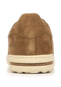Sneaker in suede marrone con retro arrotondato, suola di colore chiaro e dettagli di cucitura sottili. Presenta un accento in sughero sulla suola intermedia.