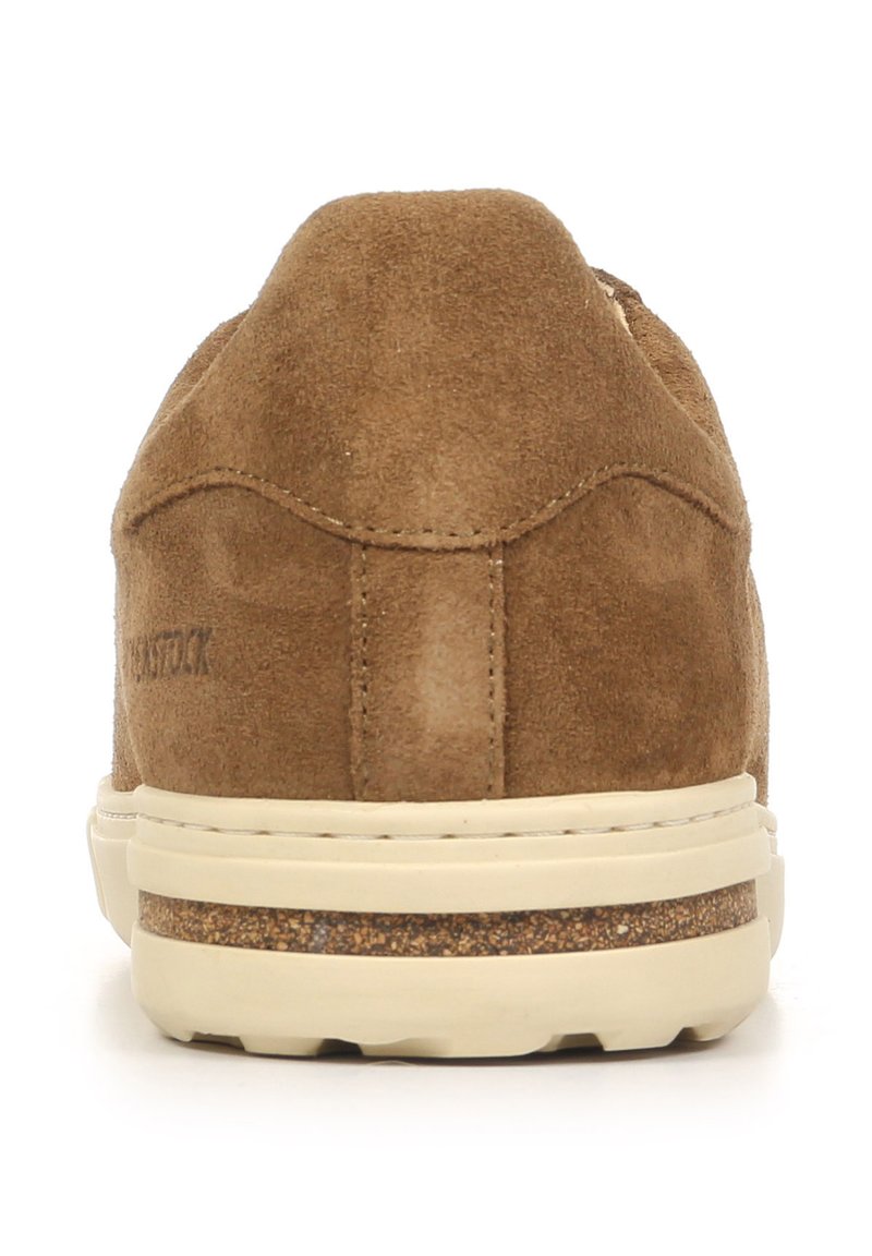Brown suede sneaker with a rounded back, light-colored outsole, and subtle stitching details. Features a cork accent on the midsole.