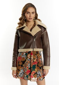 Brun læder cropped jakke med shearling krave og manchetter, med en frontlynlås og kontrasterende lysere pelskant.