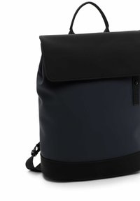 Sac à dos avec un rabat noir mat et un corps bleu foncé. Il dispose d'une poignée supérieure, d'une sangle réglable et d'un design minimaliste sans matériel visible.