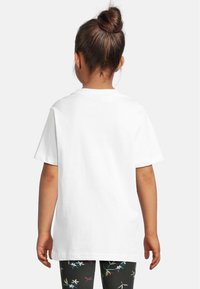 Hvit bomull t-skjorte med rund hals og korte ermer, kombinert med svarte leggings med et blomsterdesign i livlige farger.