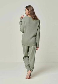 Rippstrick-Loungewear-Set in Olivgrün, bestehend aus einem locker sitzenden Pullover mit Rundhalsausschnitt und entspannten Hosen mit schmal zulaufenden Bündchen.
