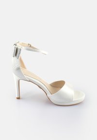 Sandal con tacco alto bianco, con punta aperta e cinturino alla caviglia, caratterizzato da un'elegante decorazione metallica testurizzata sul retro. Finitura in satin liscio.