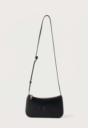Czarna skórzana torba crossbody z cienkim regulowanym paskiem, złotym zamkiem i wytłoczonym logo "CK" z przodu.