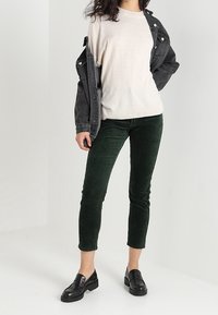 Ljusgrå stickad t-shirt, svart denimjacka, gröna kordjeans, svarta loafers. Texturerad tyg, avslappnad passform och figurnära design.