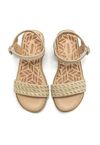 Sandalias beige con una correa de paja tejida, correa ajustable en el tobillo y una plantilla texturizada que presenta un patrón de hojas. Suela de goma plana.