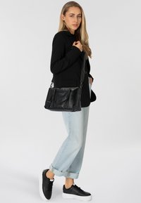 Borsa a tracolla nera in pelle con un design strutturato, dotata di manico superiore e spallaccio regolabile. Sfondo bianco semplice.