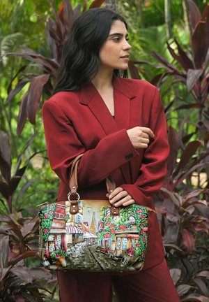Handbag featuring vibrant street scene artwork, adorned with flowers, leather accents, and a structured shape, accented by dual brown handles.