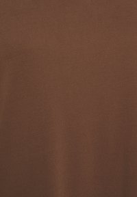Tessuto in cotone marrone con una superficie liscia e una leggera elasticità, caratterizzato da un colore uniforme senza motivi o hardware visibili.