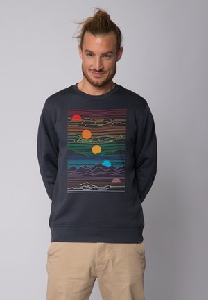 Navy sweatshirt featuring a colorful geometric mountain landscape graphic with striped patterns in orange, green, blue, and purple hues.