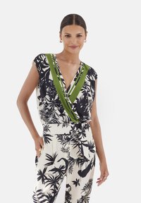 Koszulka z krótkim rękawem w kwiatowy wzór, z głębokim dekoltem w kształcie V, z zielonymi paskami i wiązanym w pasie, zestawiona z dopasowanymi spodniami w ten sam wzór.