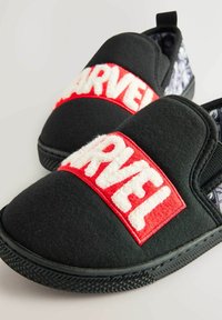 Sorte slip-on hjemmesko med en rød og hvid "MARVEL" logo-patch. Indersiden har et mønstrede foer og en tekstureret gummi sål.