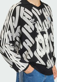 Černá a šedá vzorovaná mikina s límcem, zdobená vyšívaným logem, číslem „03“ a bílými pruhy na rukávech.