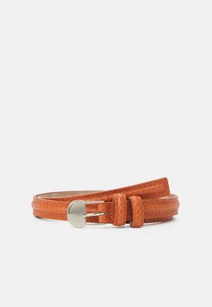 Ceinture fine en cuir orange avec un motif texturé et une boucle en métal argenté, enroulée à plat sur un fond blanc.