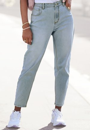 Jean en denim bleu clair taille haute avec des coutures visibles et une coupe droite, associé à des baskets blanches.