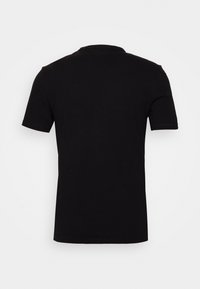 Camiseta negra de manga corta y cuello redondo, fabricada en algodón suave. La parte posterior es lisa, sin logotipos ni diseños visibles.