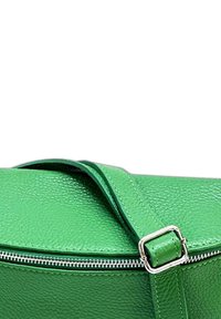 Groene leren tas met een gestructureerd oppervlak, ronde vorm, afneembare schouderriem en een zilveren ritsluiting.