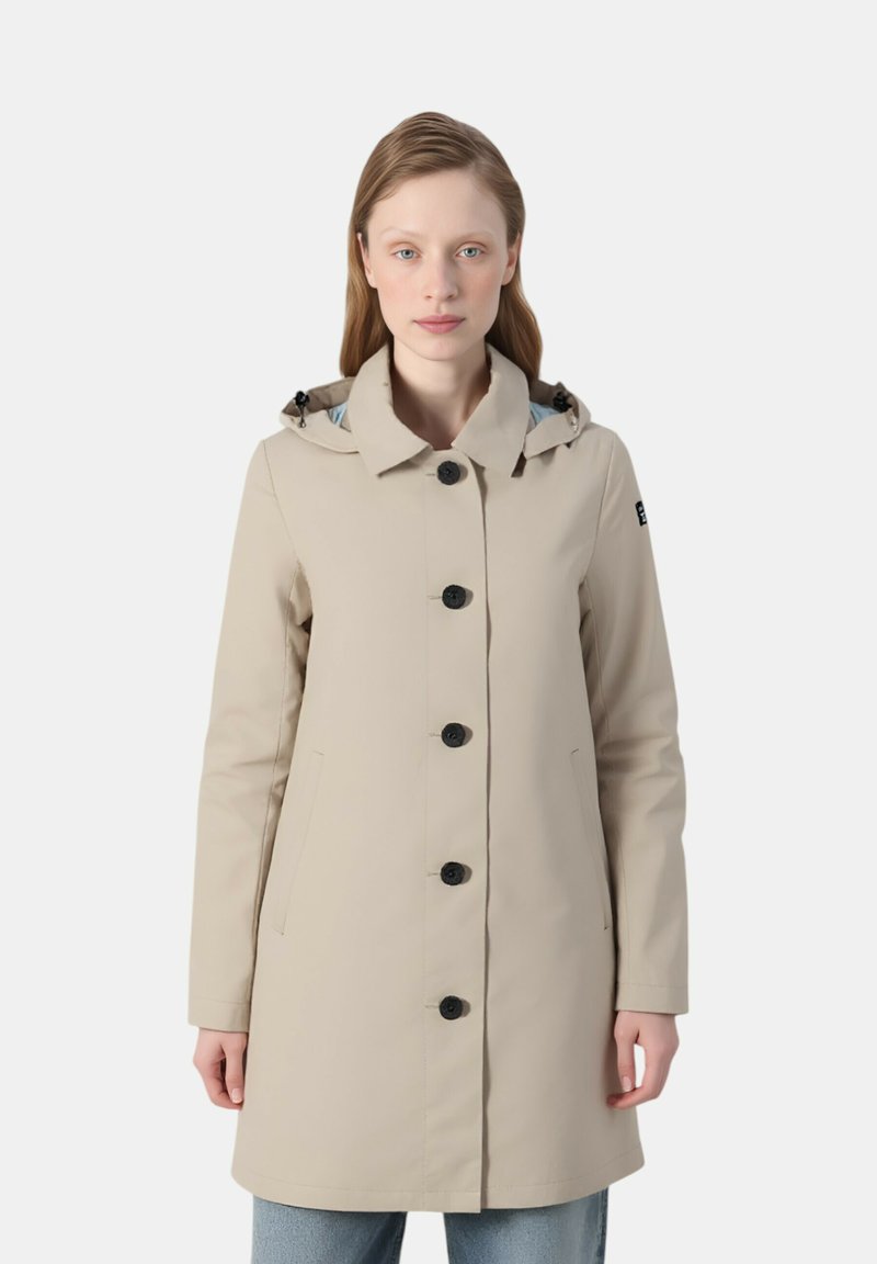 Impermeabile beige con cappuccio, dotato di bottoni neri, tasche laterali e una texture liscia. Fodera interna blu chiaro visibile sul cappuccio.