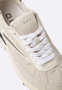Sneaker beige con tomaia in tessuto strutturato, dettagli in suede, lacci bianchi e linguetta imbottita con l'etichetta "D.A.T.E." in rilievo.