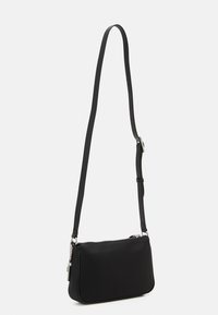 Bolso bandolera negro hecho de material texturizado, con cierre de cremallera, correa ajustable y acentos de hardware en tono plateado.