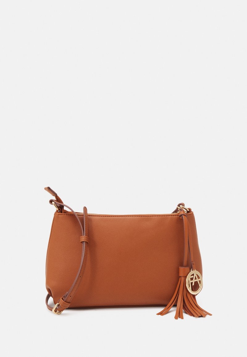 Brun læder crossbody-taske med glat tekstur, guldhardware, kvastdetalje og et præget logo på siden.