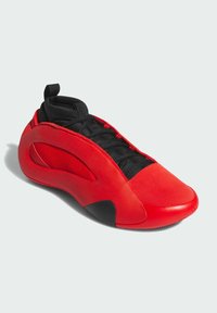 Zapatillas rojas con un diseño elegante, que presentan una combinación de materiales suaves y texturizados, acentos negros y una silueta de corte bajo.