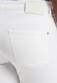 Witte denim jeans met een achterzak met een gouden klinknagel en een label met de tekst "Cambio Jeans." Soepele textuur en getailleerde pasvorm.