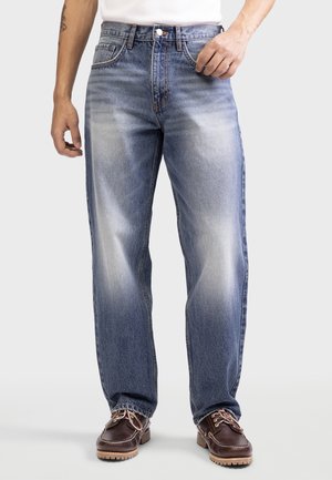 Lysblå denim jeans med lige pasform, bleget finish, kontrastsyninger og fem-lomme design, parret med brune sko.